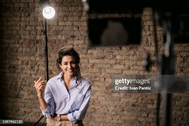 young woman giving an interview in a studio - television actress stockfoto's en -beelden