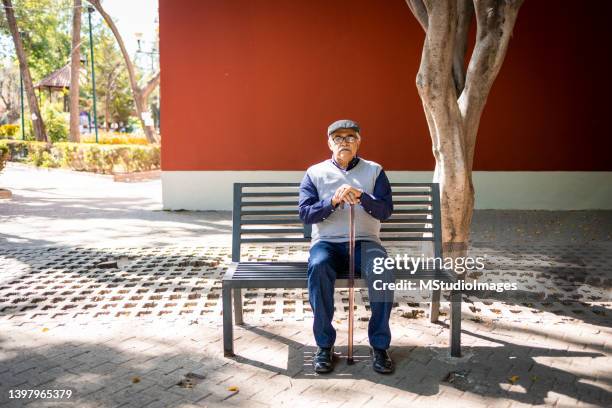 senior man sitting on the bench - walking cane stockfoto's en -beelden