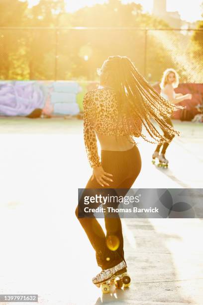 wide shot of woman roller skating in park on summer afternoon - gepardtryck bildbanksfoton och bilder