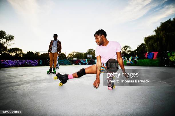 wide shot of man dancing while roller skating in park - roller skating in park stock pictures, royalty-free photos & images