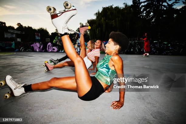wide shot of smiling female friends dancing while roller skating in park - roller skate woman fotografías e imágenes de stock