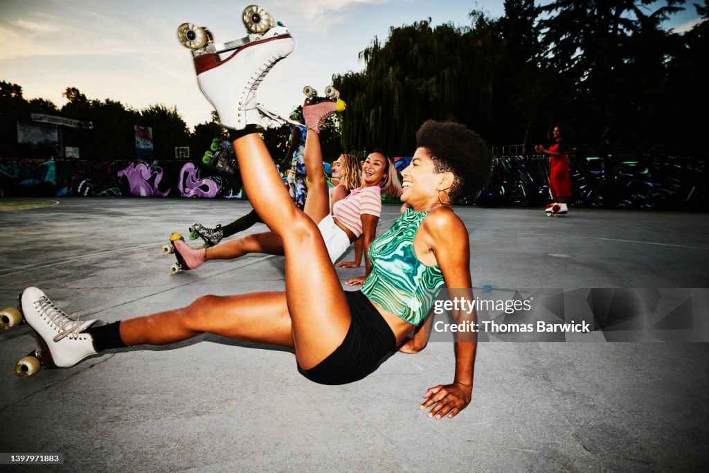 Wide shot of smiling female friends dancing while roller skating in park