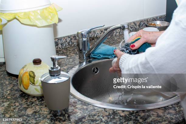 close-up of senior woman's hands washing the dishes - brillos stockfoto's en -beelden
