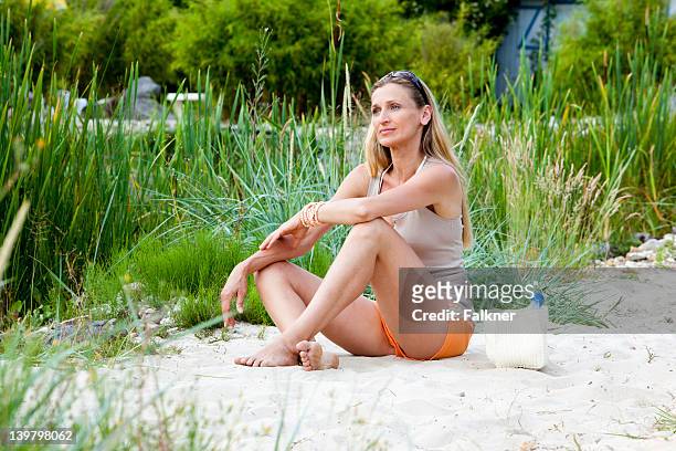 smiling woman sitting on beach - short hair photos et images de collection