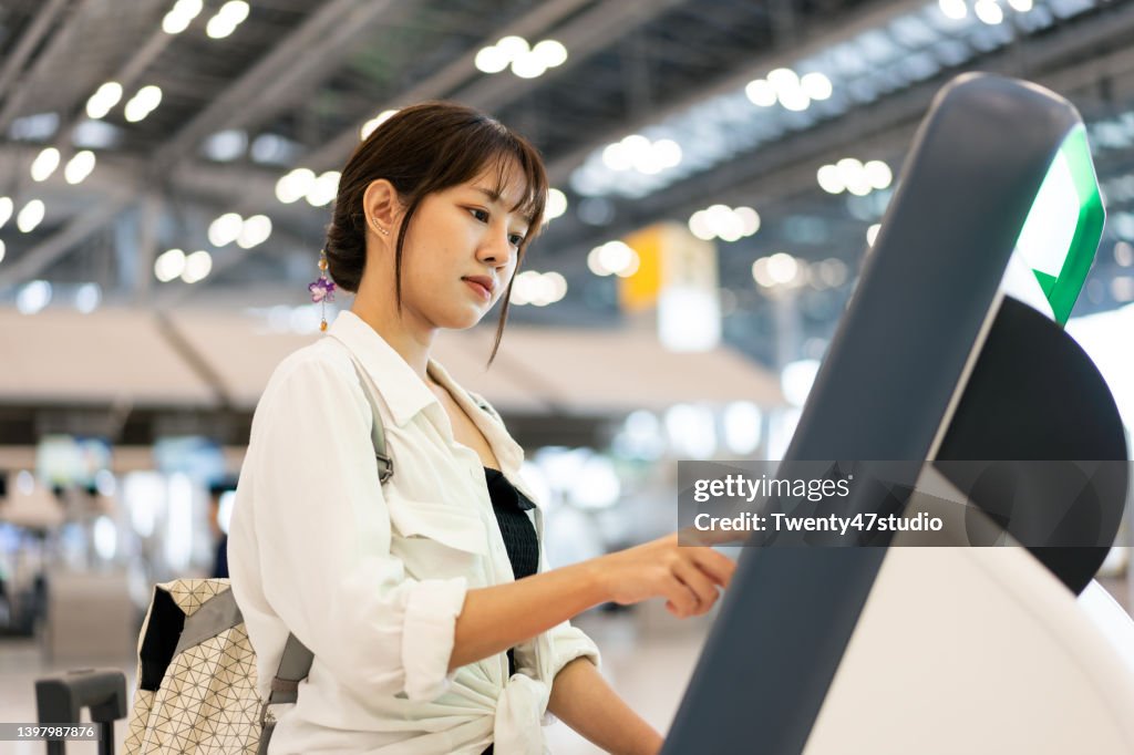 Asian young woman doing a self check-in on the kiosk machine at the airport departure terminal