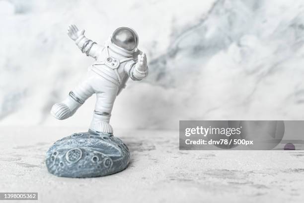 miniature astronaut balancing on moon in spacesuit waving his hand on - mini moon 個照片及圖片檔