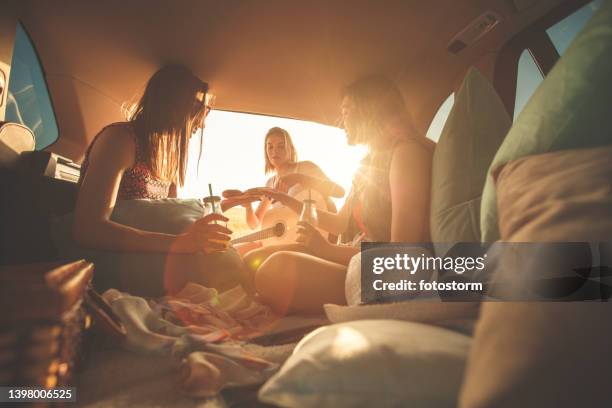 girlfriends having fun while camping in the car trunk
during sunset - buho stock pictures, royalty-free photos & images