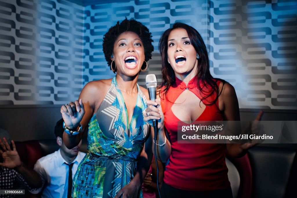 Friends singing karaoke in nightclub