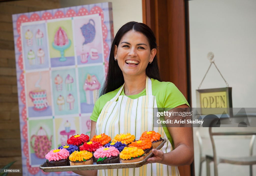 Mujer hispana bandeja de cupcakes retención