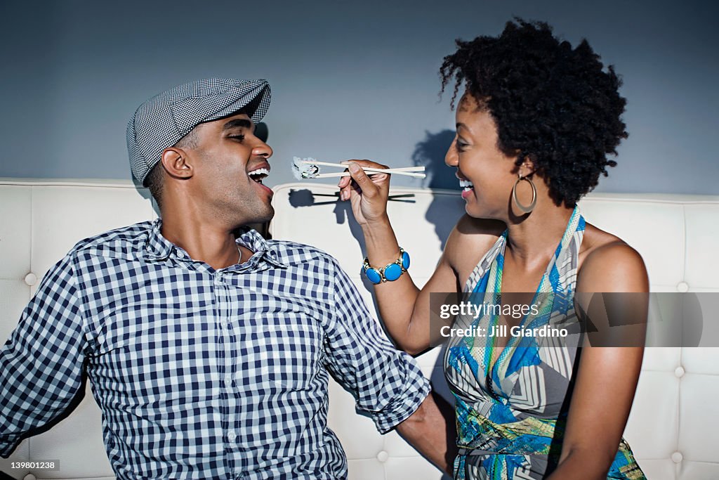 Woman feeding boyfriend sushi with chopsticks