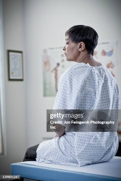 femme afro-américaine en attente dans la salle d'examen - hospital gown stock photos et images de collection