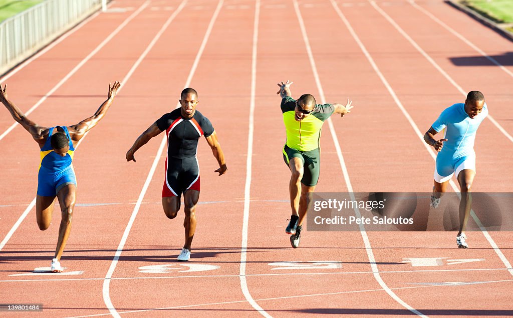 Runners running across finish line on track in race