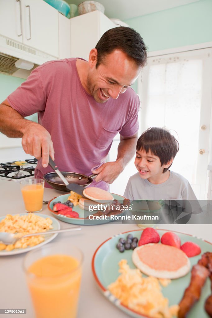 Hispanic father making breakfast for son