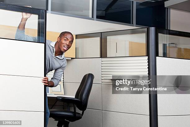 mixed race businessman peering out from office cubicle - peeking cubicle stock pictures, royalty-free photos & images