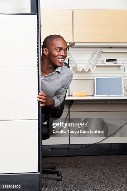 mixed race businessman peering out from office cubicle - peeking cubicle stock pictures, royalty-free photos & images