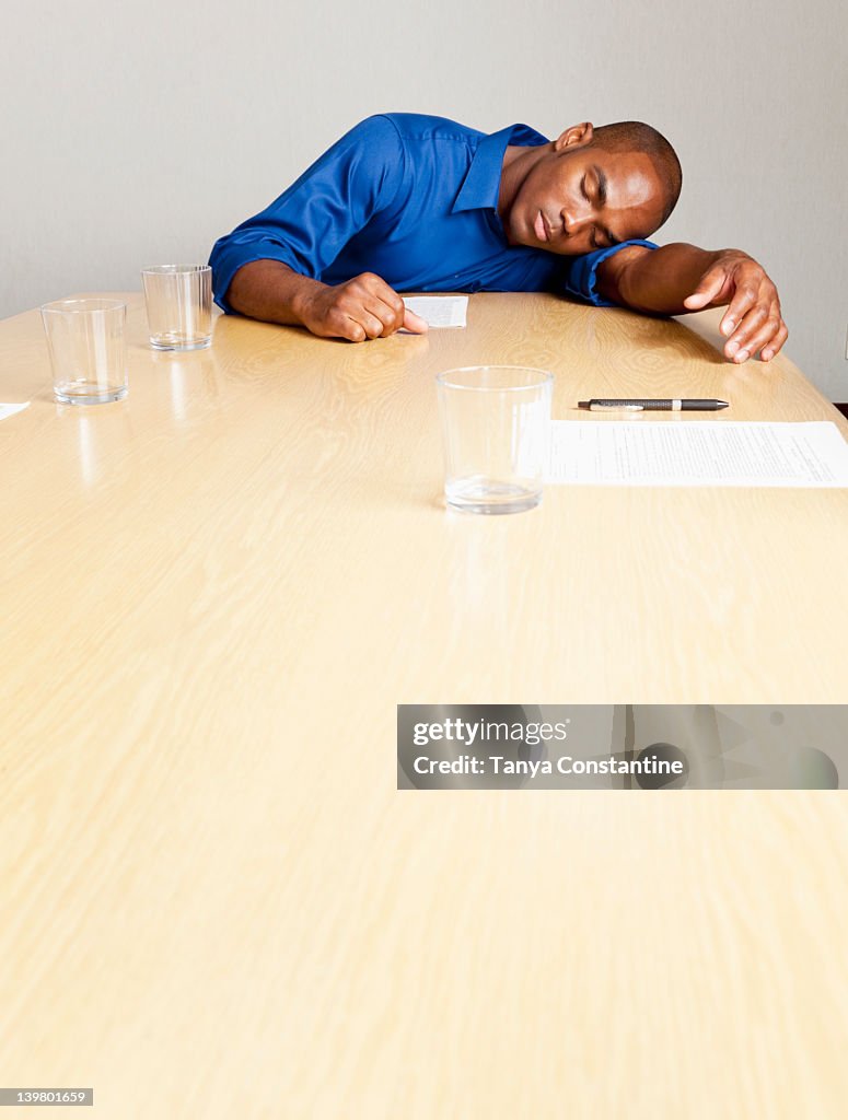 Mixed race businessman sleeping on conference room table