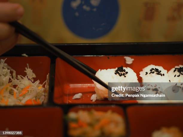 handle of the chopsticks is used to pick up the rice ball in the box on the table - cereal boxes stock pictures, royalty-free photos & images