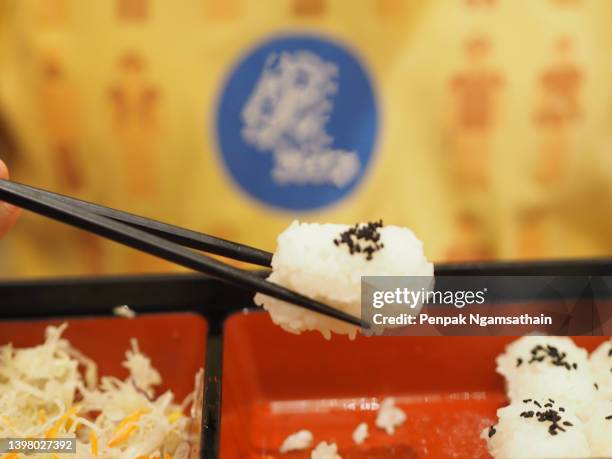 handle of the chopsticks is used to pick up the rice ball in the box on the table - nigiri stockfoto's en -beelden