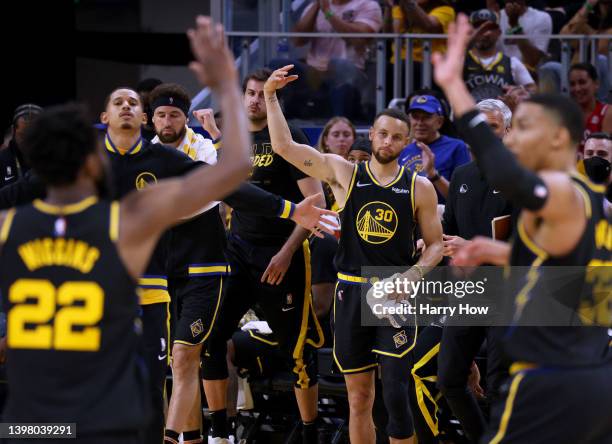 Stephen Curry of the Golden State Warriors celebrates a lead after a timeout with Andrew Wiggins and Otto Porter Jr. #32 in a 112-87 Warriors win...