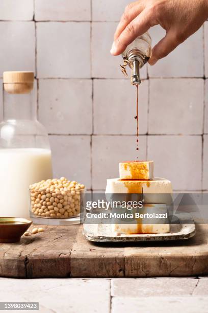 meat substitute products on wooden board, human hand pouring soy sauce - sojamilch stock-fotos und bilder