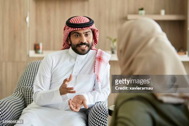 middle eastern man and woman conversing in family home - candid forum stockfoto's en -beelden