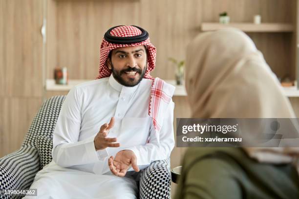 middle eastern man and woman conversing in family home - saudi man bildbanksfoton och bilder