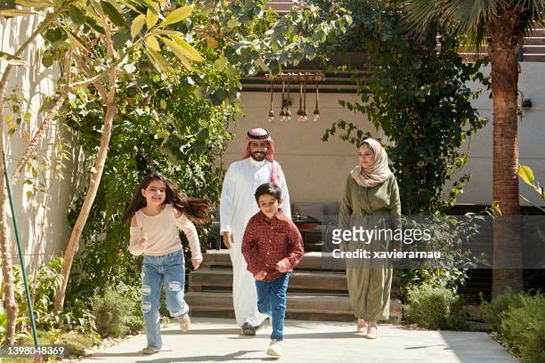 active saudi children outdoors with their parents - arab woman walking stockfoto's en -beelden
