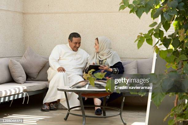 riyadh couple using digital tablet on home patio - ksa people stock pictures, royalty-free photos & images