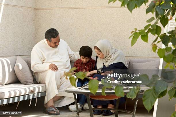 saudi boy and grandparents using digital tablet - saudi grandfather stock pictures, royalty-free photos & images