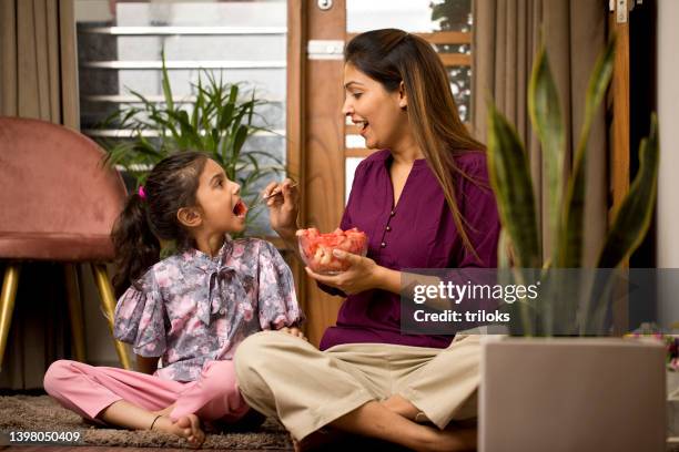 happy mother feeding fruit to daughter at home - eating stock pictures, royalty-free photos & images
