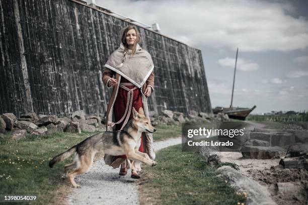 a beautiful blonde viking woman and dog outdoors on a settlement - ancient vikings stockfoto's en -beelden