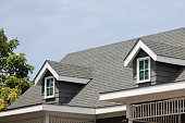 Roof shingles with garret house on top of the house. dark asphalt tiles on the roof background on afternoon time. dark asphalt tiles on the roof background