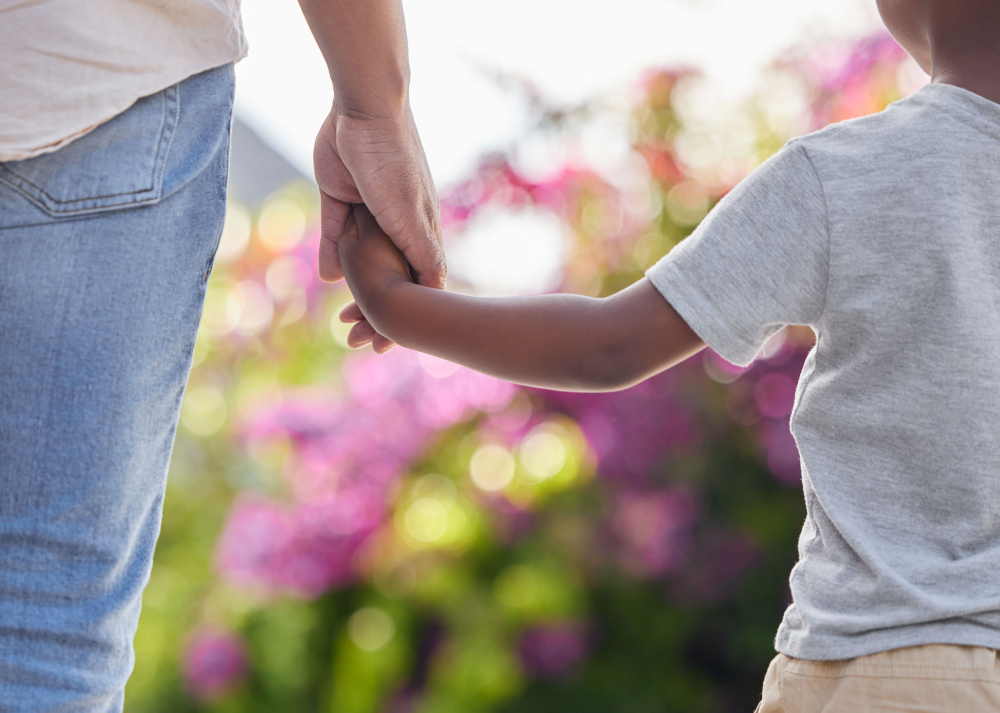 Closeup father and son holding hands while walking outside in the garden. A great role model and mentor for his boy child. A son will always look up to and follow in their dad's footsteps Closeup father and son holding hands while walking outside in the garden. A great role model and mentor for his boy child. A son will always look up to and follow in their dad's footsteps
