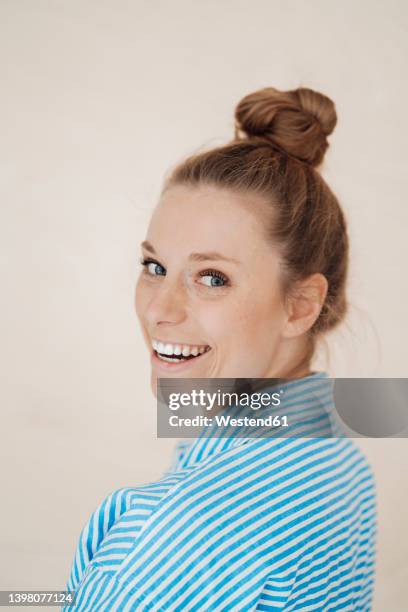 happy businesswoman with hair bun looking over shoulder - offenes lächeln stock-fotos und bilder