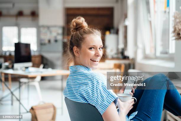 cheerful businesswoman looking over shoulder sitting at home - regarder par dessus son épaule photos et images de collection