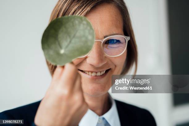 happy businesswoman showing green leaf - green economy stock-fotos und bilder