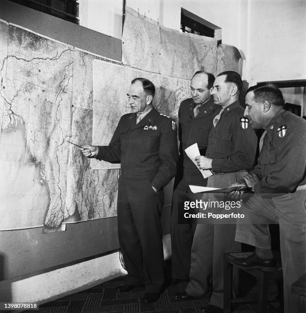 Lieutenant General Daniel Isom Sultan of the United States Army, Commander of the India-Burma Theater, on left, pointing to a map of Burma with, from...