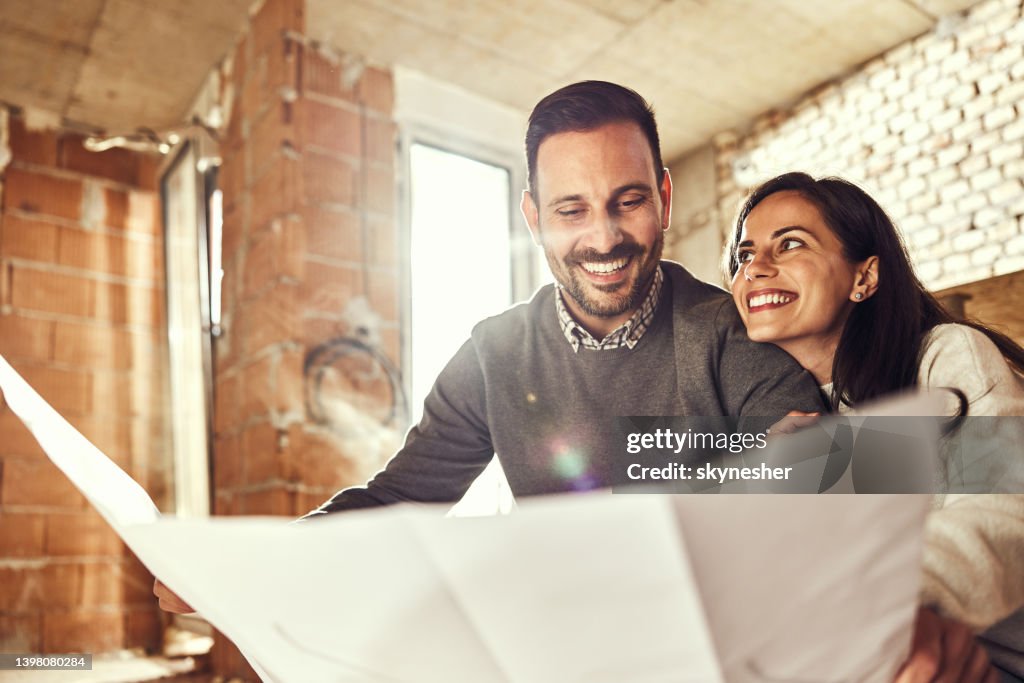 Glückliches Paar analysiert Pläne in ihrer Renovierung Wohnung.
