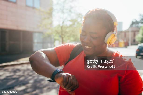 happy woman listening music checking time on smart watch - 48 hours stock-fotos und bilder