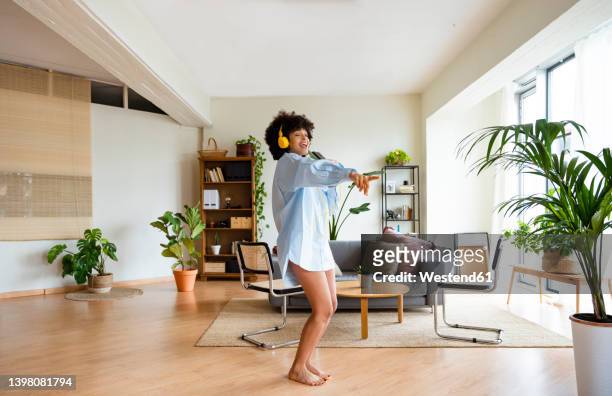 happy young woman wearing headphones enjoying music at home - singing fotografías e imágenes de stock