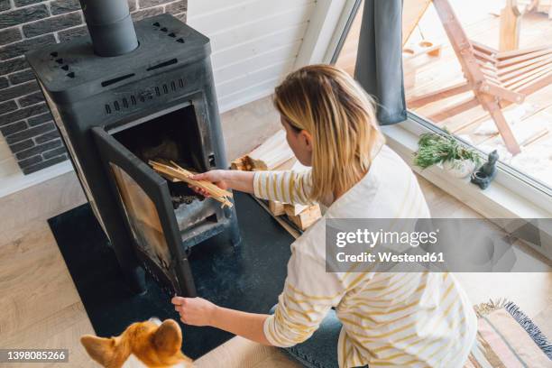 woman putting wood in fireplace at home - brasved bildbanksfoton och bilder