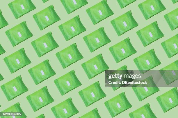 pattern of sanitary napkins packed in green paper on green background. concept of menstruation, ovulation, reproduction, pain and personal hygiene. - tampon menstruation stock-fotos und bilder