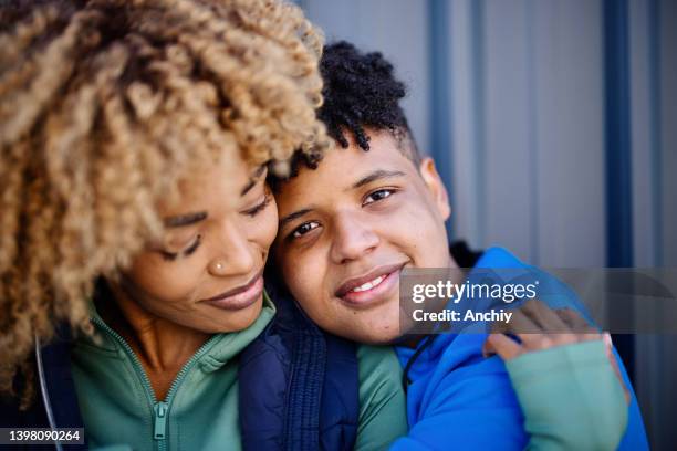 portrait d’un fils adolescent et d’une mère adulte en train de s’embrasser - black mom photos et images de collection
