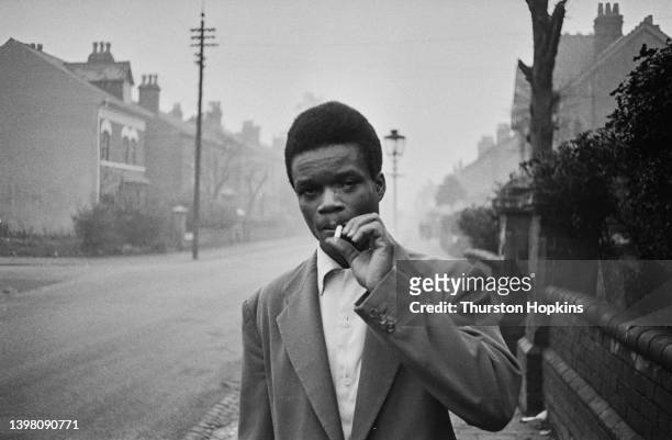 Man smokes a cigarette on an unspecified street in Birmingham, UK. Original Publication: Picture Post - 7482 - Vol 66 No 4 - Are we building up to a...