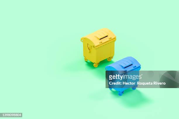 yellow and blue garbage container in green background, 3d render - müllcontainer stock-fotos und bilder