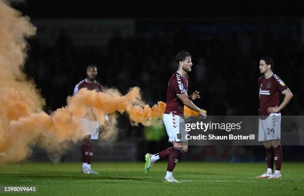 Fraser Horsfall of Northampton Town removes a flare from the pitch during the Sky Bet League Two Play-off Semi Final 2nd Leg match between...