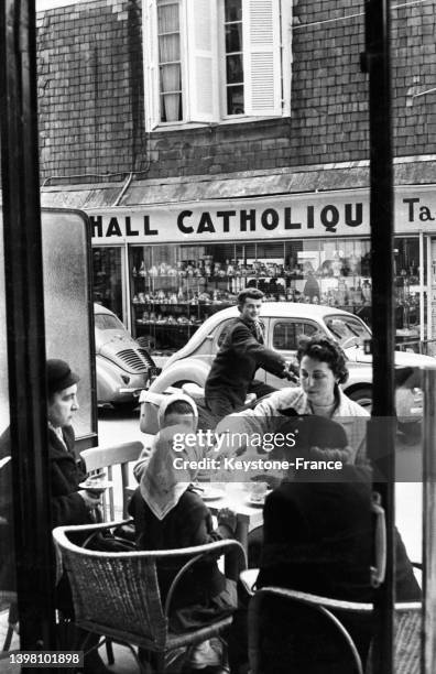 Terrasse de café devant une boutique de souvenirs à Lourdes, en mars 1958.