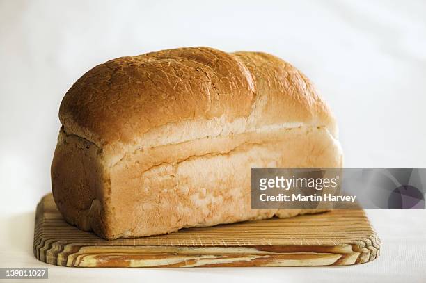 loaf of white bread on cutting board.against white background. - loaf of bread foto e immagini stock