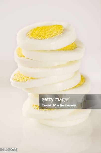 stacked slices of boiled egg. studio shot against white background. - boiled stock pictures, royalty-free photos & images