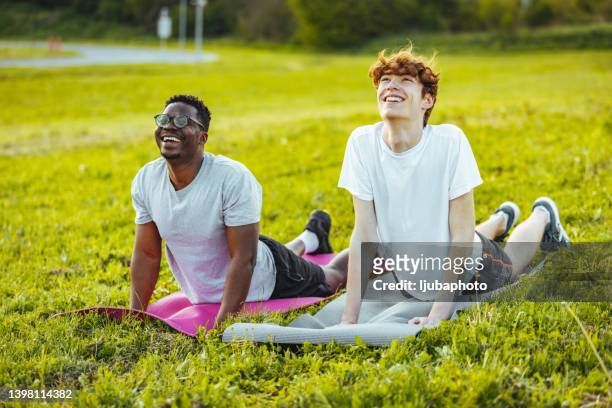 multi ethnic friends on outdoors training, doing yoga and stretching - teenager yoga stock pictures, royalty-free photos & images